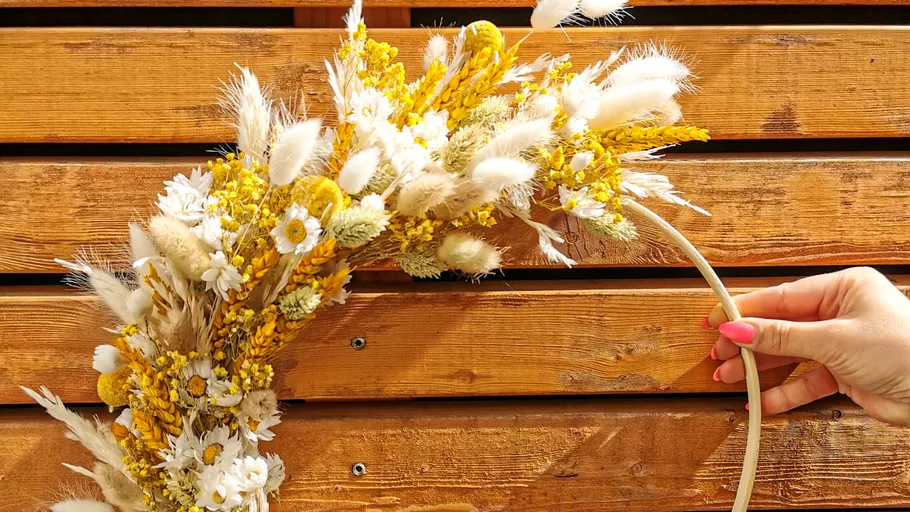 Hand holding dried flower wreath outdoors.
