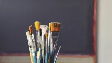 Paintbrushes in front of a canvas.