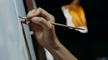 Hand painting on canvas in dim lighting.