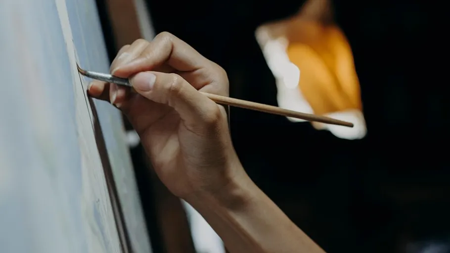 Hand painting on canvas in dim lighting.