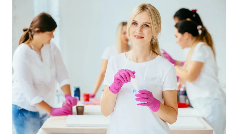 Women in pink gloves working on crafts together.