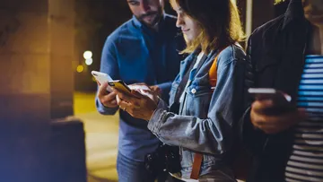 Menschen benutzen Smartphones draußen nachts.