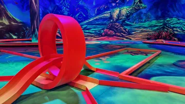 Mini golf loop with dinosaur mural background.