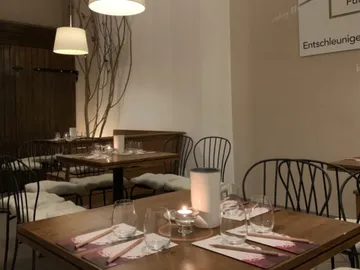 Tische mit Kerzen und Gläsern in einem Restaurant.