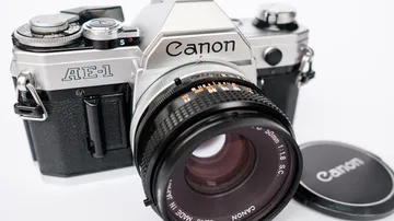 Canon AE-1 camera with lens cap nearby.