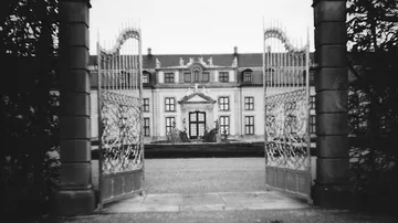 Verzierte Tore öffnen Blick auf großes Gebäude.
