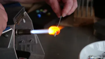 Person formt Glas mit Flammenbrenner.