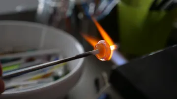 Glasperle wird mit Flamme geformt, Werkstatthintergrund.