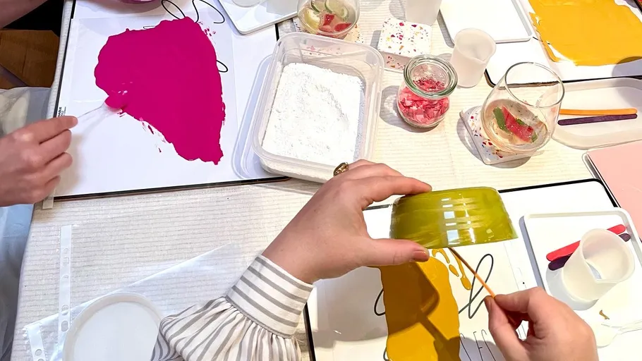 Hands creating art with paints and tools.