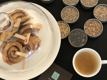 Zimtschnecken unter einer Glasglocke, umgeben von Kaffeebohnen.