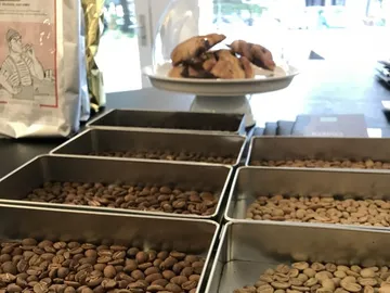 Kaffeebohnen in Schalen, Kekse auf einem Teller darunter.