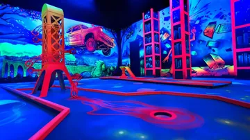 Neon-lit mini-golf course with surreal artwork.