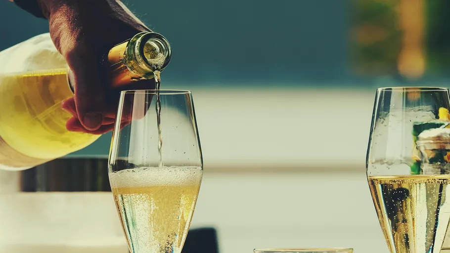Hand pouring champagne into two glasses.