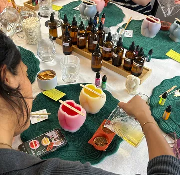 Person making candles with essential oils, indoors.