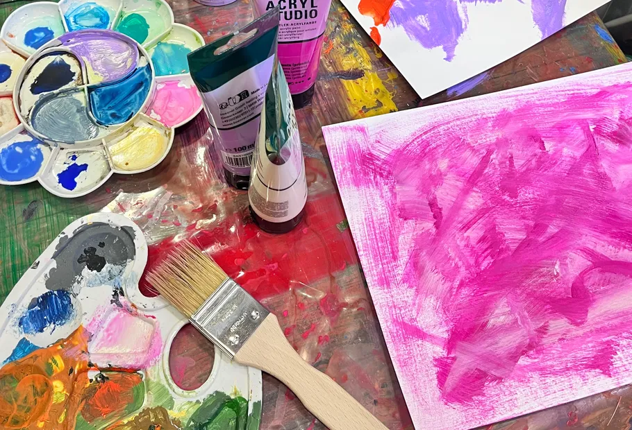 Paintbrush and palettes on cluttered artistic table.