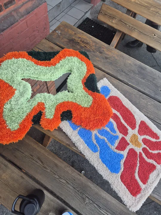 Two colorful rugs on wooden picnic table.