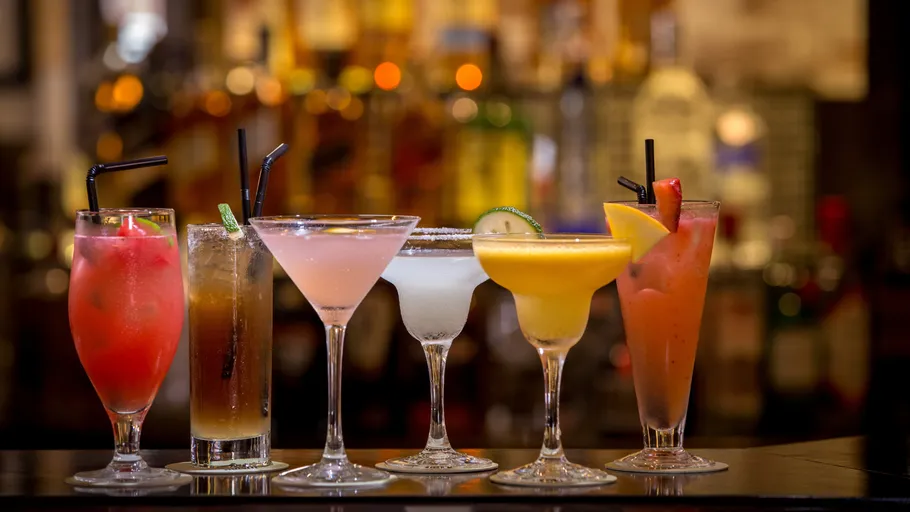 Colorful cocktails lined up at a bar.