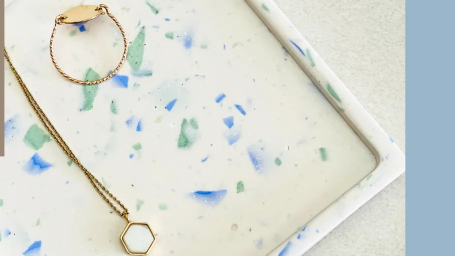 Gold jewelry on a speckled tray.
