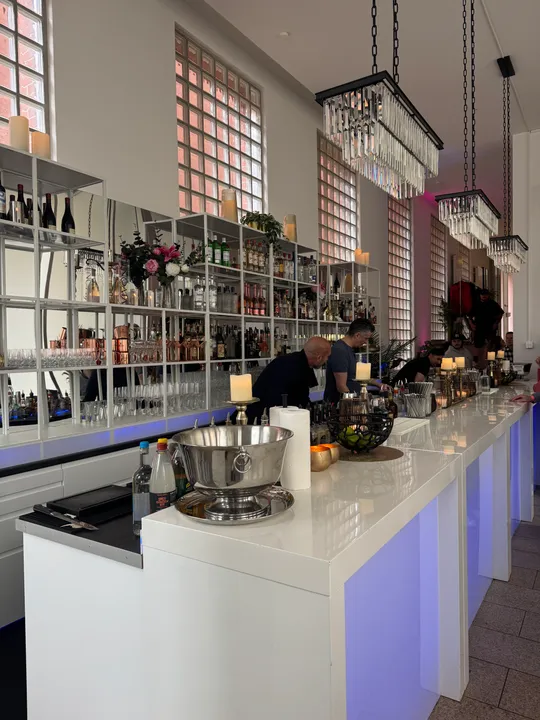 Modern bar interior with shelves and lighting.