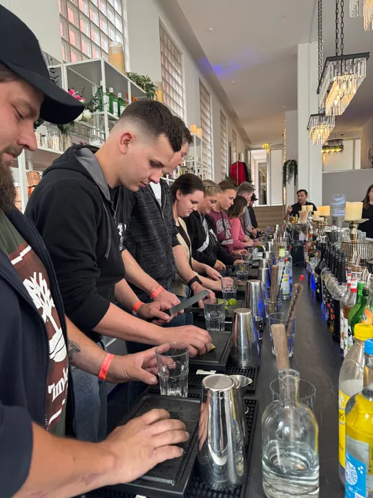 People preparing drinks at a bar counter.