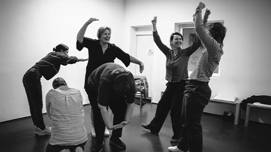People forming letters with bodies indoors joyfully.