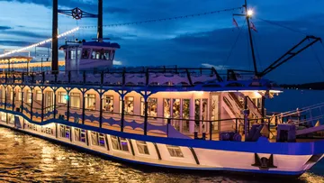 Paddle steamer sails on a twilight river.
