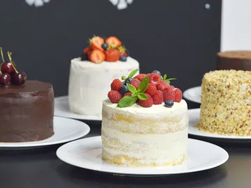 Mehrere Kuchen stehen auf Tellern, dekoriert mit Früchten.