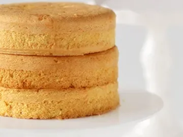 Drei übereinanderliegende Biskuitkuchen auf einem Teller.