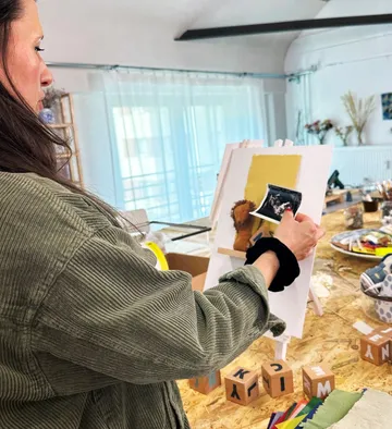 Woman arranging blocks and picture on table.