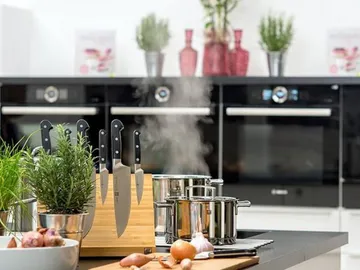 Kitchen countertop with cookware, steaming, modern environment.