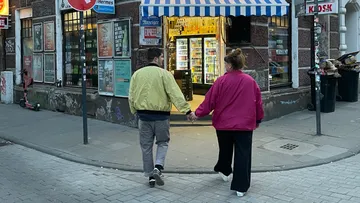 Paar Hand in Hand geht an einem Laden vorbei.