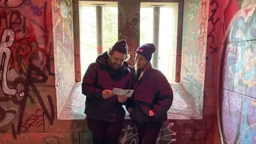 Two people reading in front of graffiti.