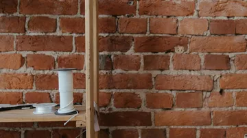 Spools of wire on a wooden shelf, brick wall.