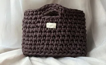 Brown crocheted basket on white fabric.