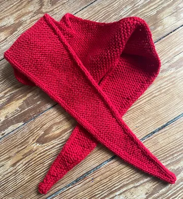 Red knitted scarf on wooden floor.