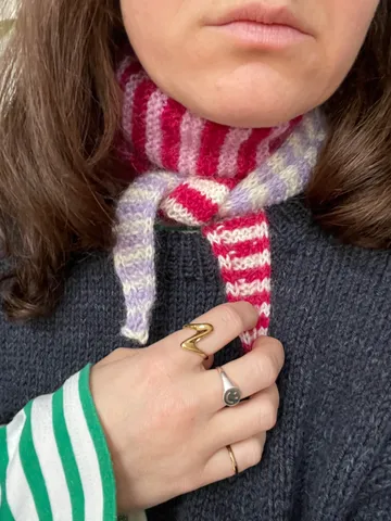 Striped scarf around neck, hand holds it.