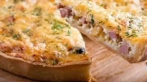 Quiche slice being served on wooden board.