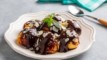 Dessert balls with chocolate sauce on plate.
