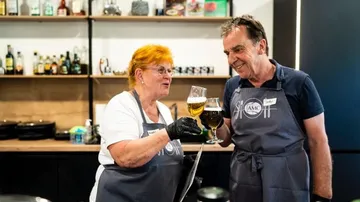 Zwei Personen stoßen mit Bier in der Küche an.