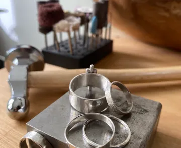 Silver rings and tools on a wooden table.