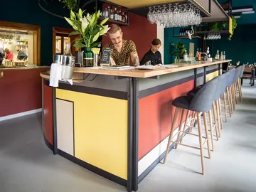 Barkeeper steht an einer farbenfrohen, modernen Bar.