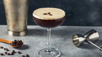 Espresso martini on table with coffee beans.