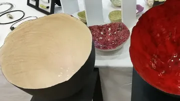 Three ceramic bowls on black pedestals.