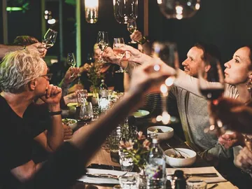 Group raising glasses at dinner party.