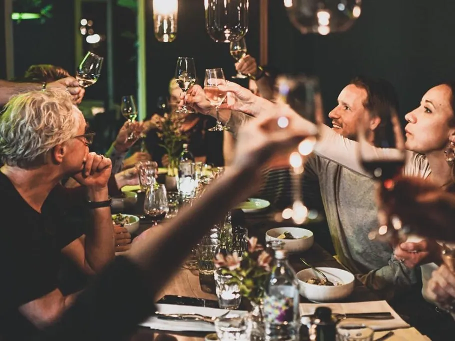 Group raising glasses at dinner party.