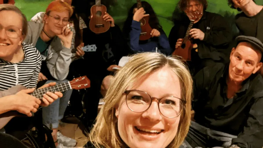 Group of people playing ukuleles indoors.