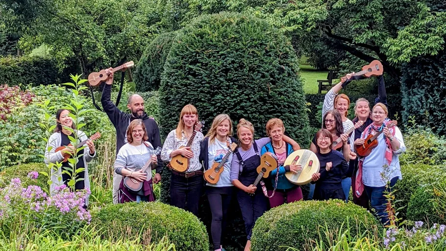 Group with ukuleles in garden setting.