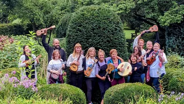 Group holding ukuleles in a garden.
