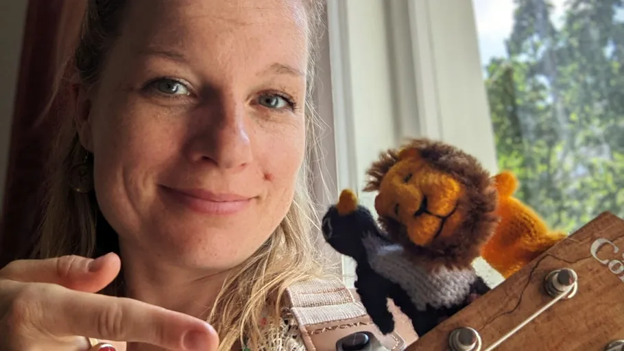 Woman smiling, finger pointing, holding stuffed lion.