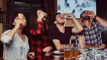 Gruppe trinkt Schnaps an einer Bar.